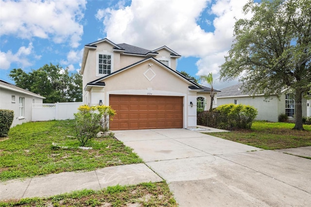 traditional-style home with a garage, fence, driveway, stucco siding, and a front yard