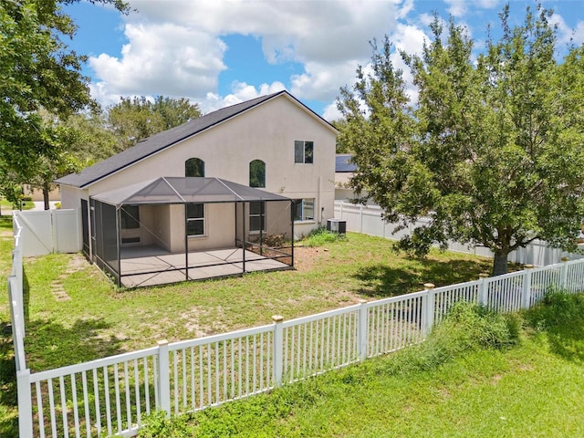 back of house with a patio, a fenced backyard, a lanai, a yard, and stucco siding