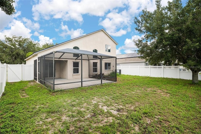 back of property featuring a patio, central AC unit, a fenced backyard, a lanai, and a lawn