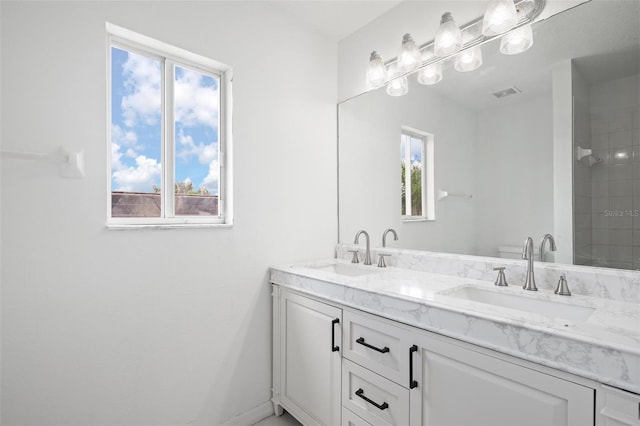 full bathroom with tiled shower, a sink, visible vents, and double vanity