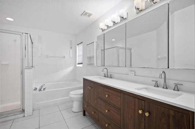 full bath with tile patterned flooring, a sink, a shower stall, and a textured ceiling