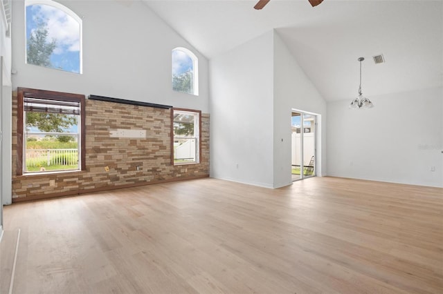 unfurnished living room featuring light wood-style floors, a healthy amount of sunlight, visible vents, and ceiling fan with notable chandelier