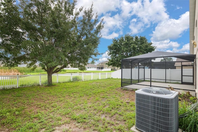 view of yard with glass enclosure, a fenced backyard, and central AC unit