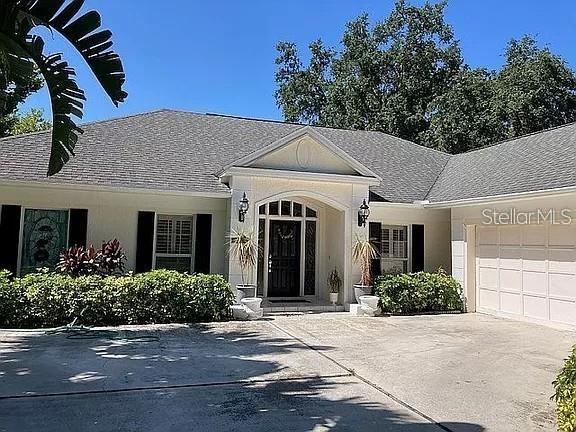 ranch-style house featuring a garage, driveway, and stucco siding