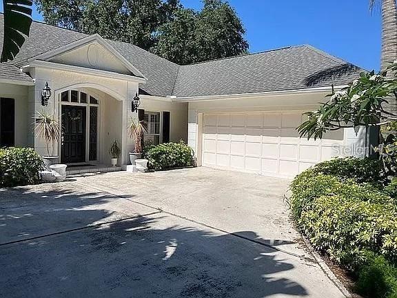 view of front of house featuring a garage, driveway, and roof with shingles