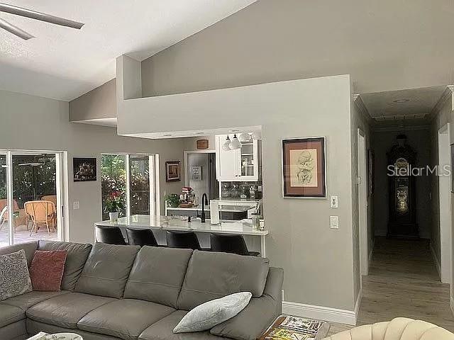 living area featuring lofted ceiling and baseboards