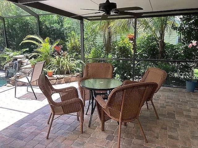 view of patio featuring glass enclosure and a ceiling fan