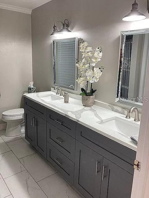 bathroom with marble finish floor, a sink, and double vanity