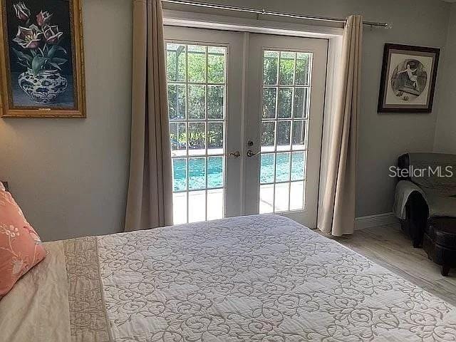 bedroom with access to outside, baseboards, wood finished floors, and french doors