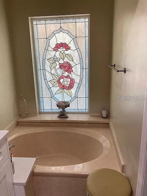 bathroom featuring a garden tub and vanity