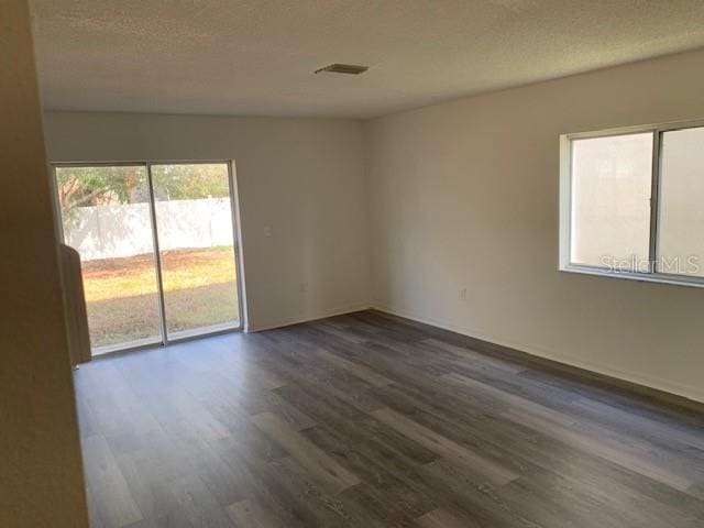 spare room with a textured ceiling, dark wood finished floors, and visible vents