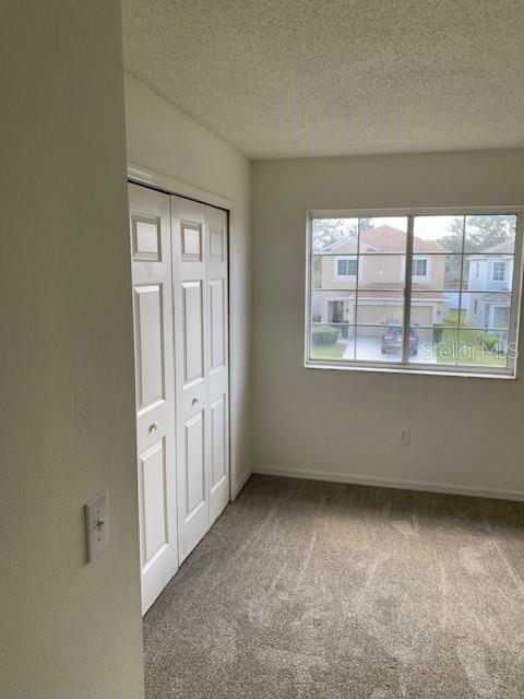 unfurnished bedroom featuring carpet floors, a closet, baseboards, and a textured ceiling