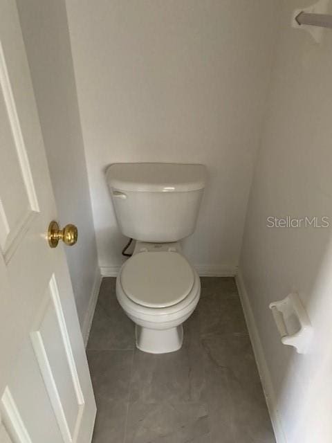 bathroom with tile patterned floors, toilet, and baseboards