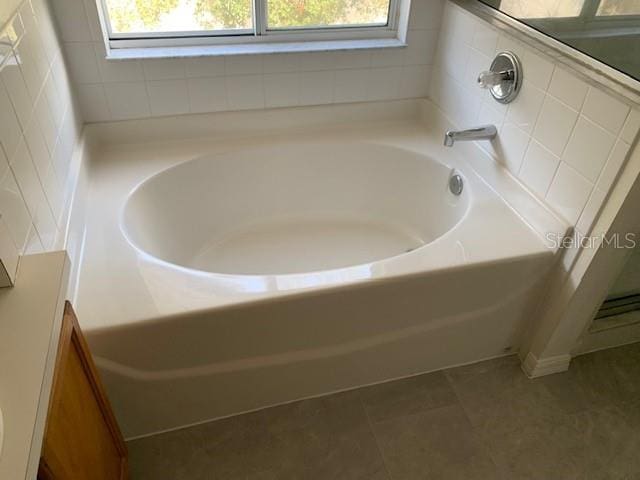 full bath with a healthy amount of sunlight, a garden tub, and tile patterned floors