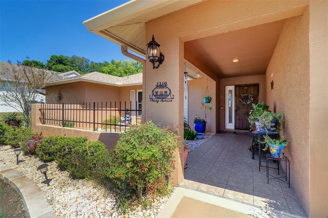 entrance to property featuring fence and stucco siding