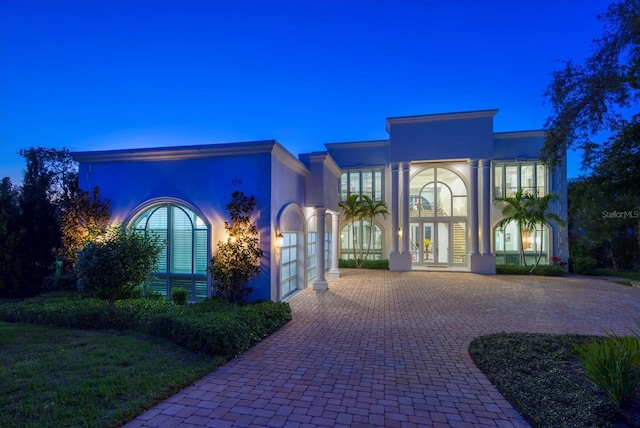 view of front of property featuring a garage, french doors, decorative driveway, and stucco siding