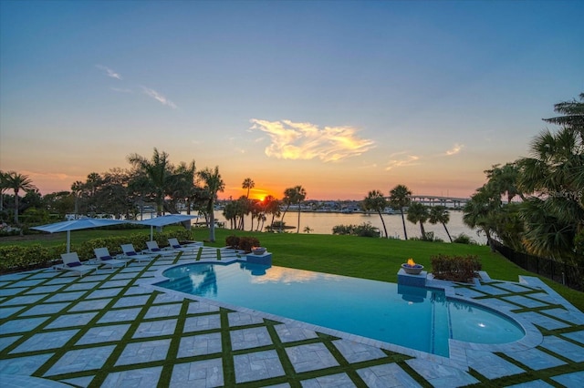 view of swimming pool with an infinity pool, a water view, a yard, and a patio