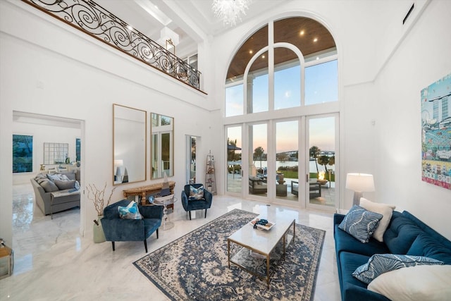 living area with marble finish floor, a notable chandelier, and a high ceiling