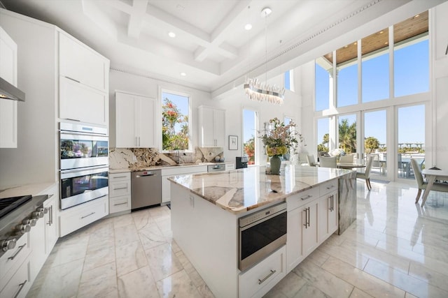 kitchen with a center island, marble finish floor, stainless steel appliances, decorative backsplash, and coffered ceiling