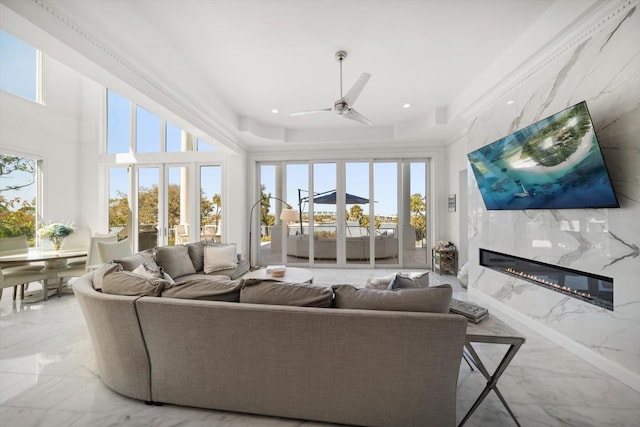 living area featuring a wealth of natural light, marble finish floor, a fireplace, and ceiling fan