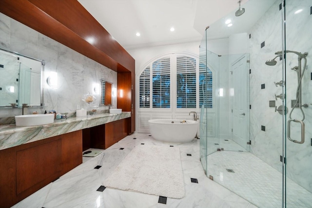 bathroom featuring tile walls, double vanity, a stall shower, a sink, and a freestanding tub