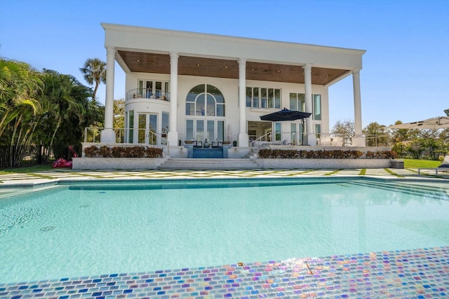 back of property featuring a patio, a balcony, french doors, a fenced in pool, and stucco siding