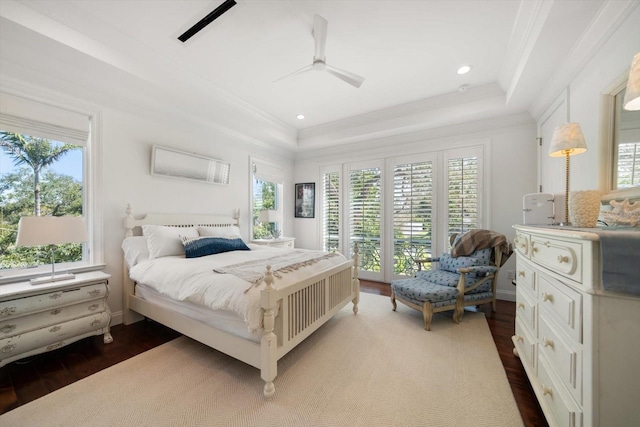 bedroom with crown molding, multiple windows, a tray ceiling, and wood finished floors