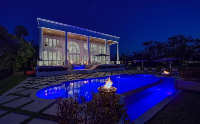 pool at twilight featuring a patio area, an outdoor pool, and french doors