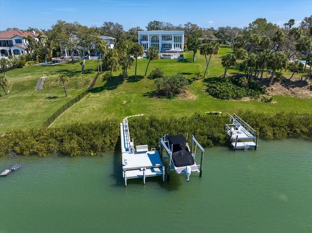 view of dock featuring a water view, boat lift, and a yard