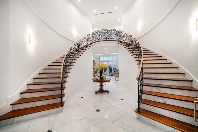 stairway with marble finish floor, arched walkways, and recessed lighting