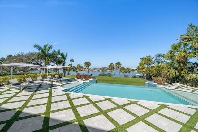 outdoor pool featuring a yard, a water view, and a patio