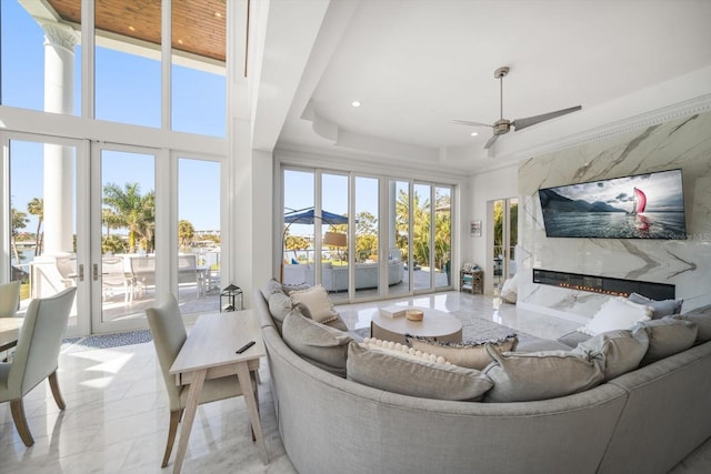 living area featuring ceiling fan, french doors, plenty of natural light, and a fireplace