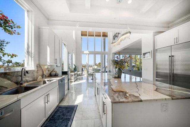 kitchen with a large island, appliances with stainless steel finishes, light stone counters, and a sink