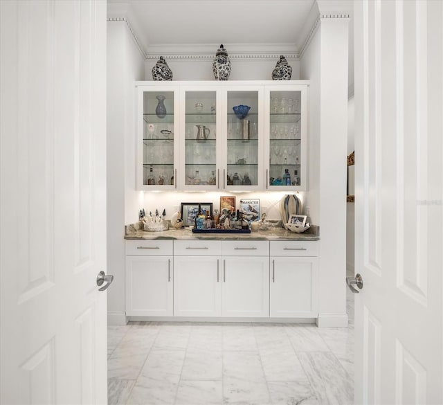 bar with marble finish floor, crown molding, and a dry bar