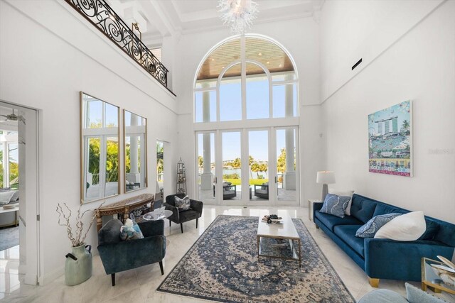 living room featuring light tile patterned floors, a towering ceiling, beamed ceiling, crown molding, and a chandelier