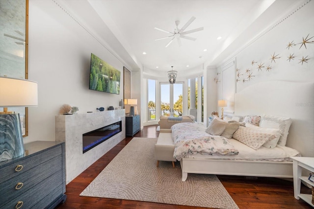 bedroom featuring recessed lighting, wood finished floors, and a glass covered fireplace