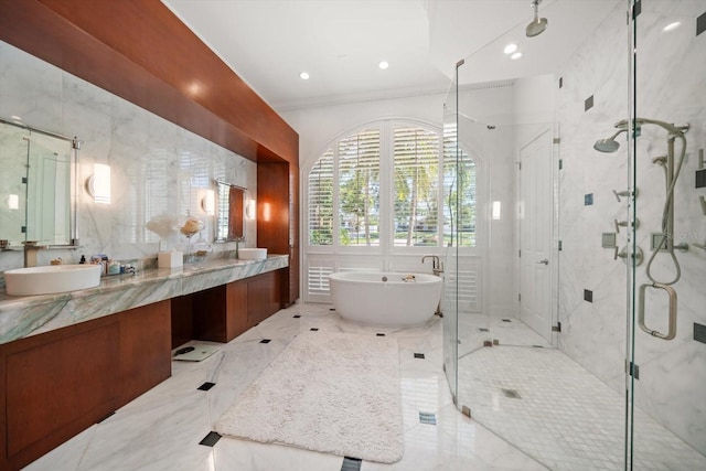 full bathroom with double vanity, a stall shower, a sink, a freestanding bath, and tile walls