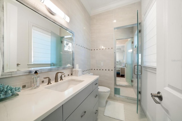 ensuite bathroom with connected bathroom, toilet, crown molding, vanity, and tile walls