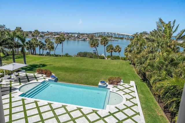 pool with a water view, a patio area, and a lawn