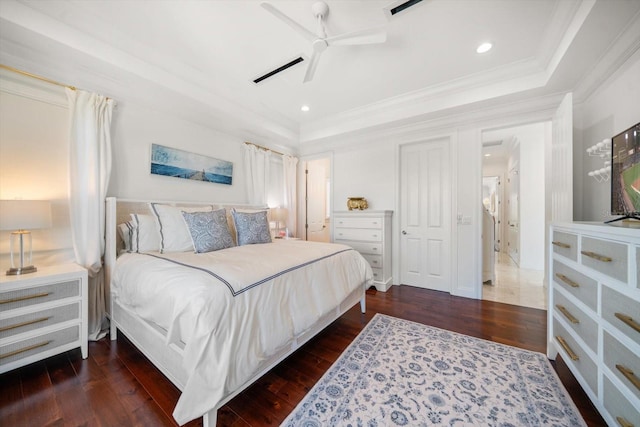 bedroom featuring dark wood-type flooring, recessed lighting, a raised ceiling, and crown molding