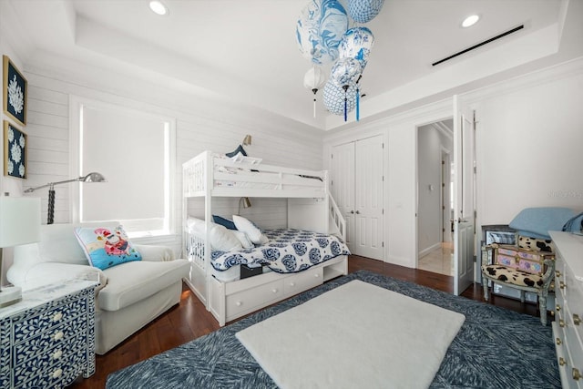 bedroom featuring a tray ceiling, recessed lighting, a closet, visible vents, and wood finished floors