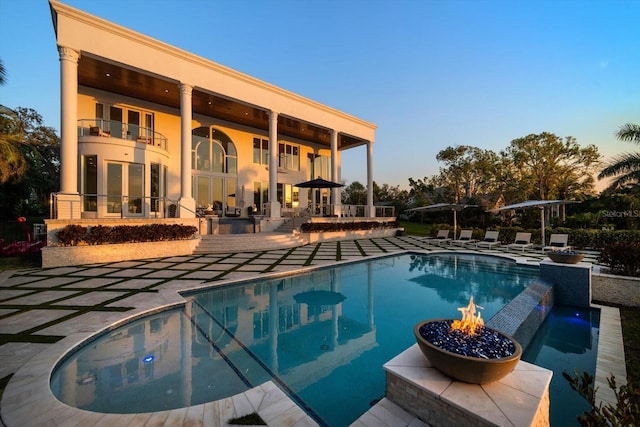 view of swimming pool featuring a pool with connected hot tub, a patio, a fire pit, and french doors