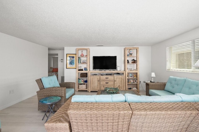 living area featuring light wood-style flooring, a textured ceiling, and baseboards