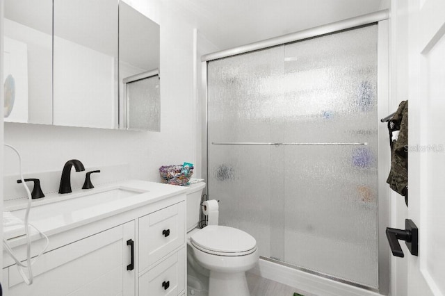 bathroom with a stall shower, toilet, and vanity