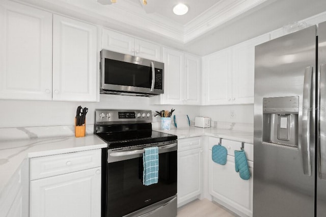 kitchen featuring light stone counters, white cabinets, stainless steel appliances, and ornamental molding