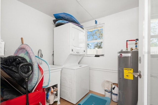 laundry area with stacked washer and dryer, electric water heater, and laundry area