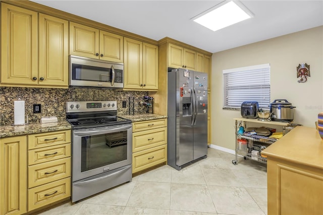 kitchen featuring light tile patterned floors, tasteful backsplash, baseboards, and stainless steel appliances