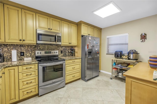 kitchen featuring light tile patterned floors, light stone counters, baseboards, appliances with stainless steel finishes, and tasteful backsplash