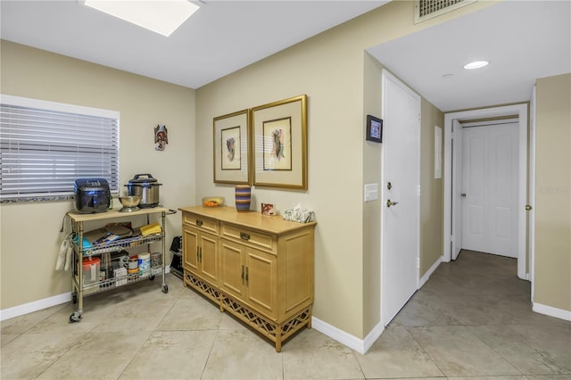 hallway featuring light tile patterned flooring, visible vents, and baseboards