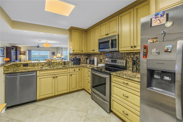 kitchen with light tile patterned floors, backsplash, appliances with stainless steel finishes, a sink, and dark stone counters